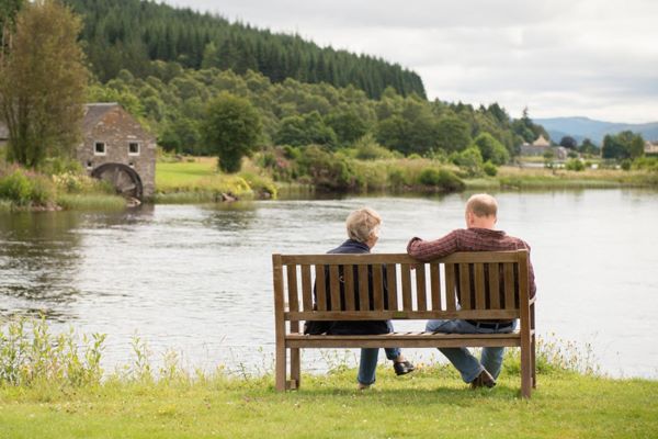customers sitting outside Loch Tummel Hotel on a wooden bench in front of the Loch